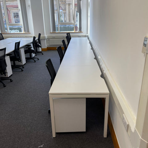 Single width row of used white bench desks in an office in London.