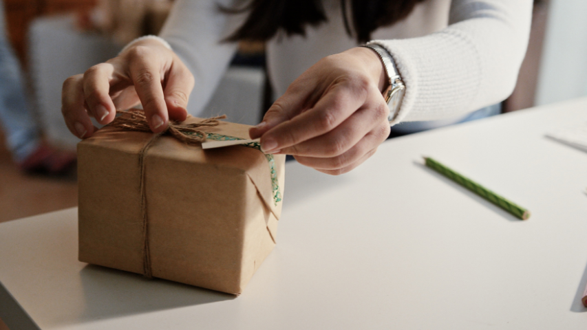 Person’s hands opening up a package delivered to them by their long-distance partner.