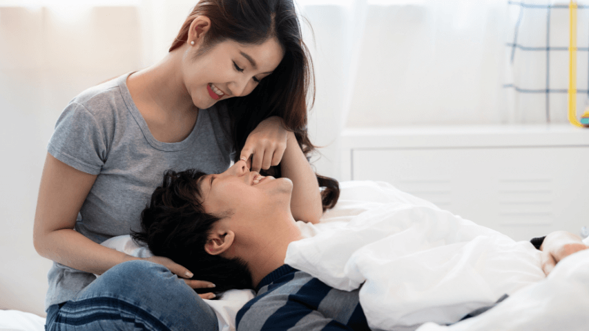 Une femme touchant le nez de son partenaire qui a la tête couchée sur ses cuisses.