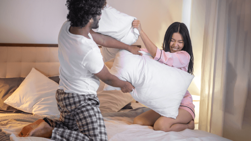 Two people having a playful pillow fight.
