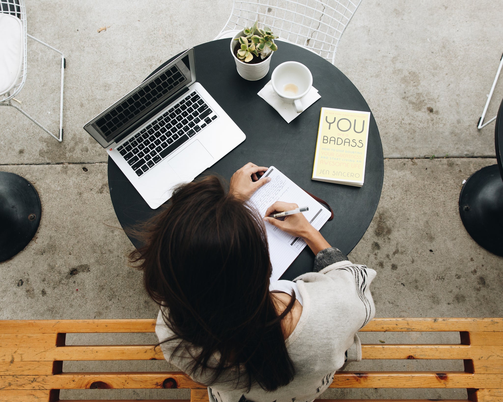 Person with planner, laptop, and book at a coffee table