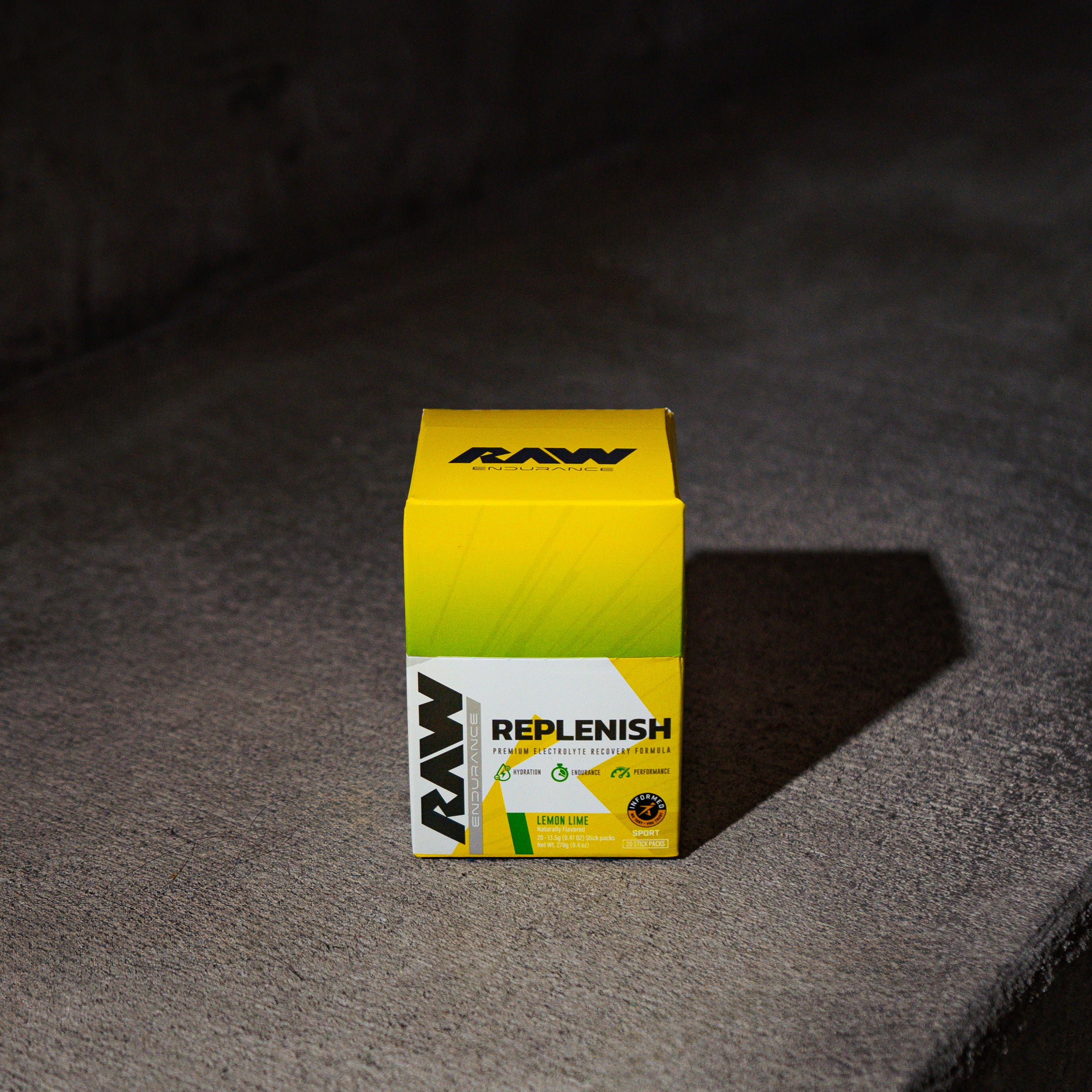 A brightly colored product box labeled 'RAW Replenish' on a concrete surface.