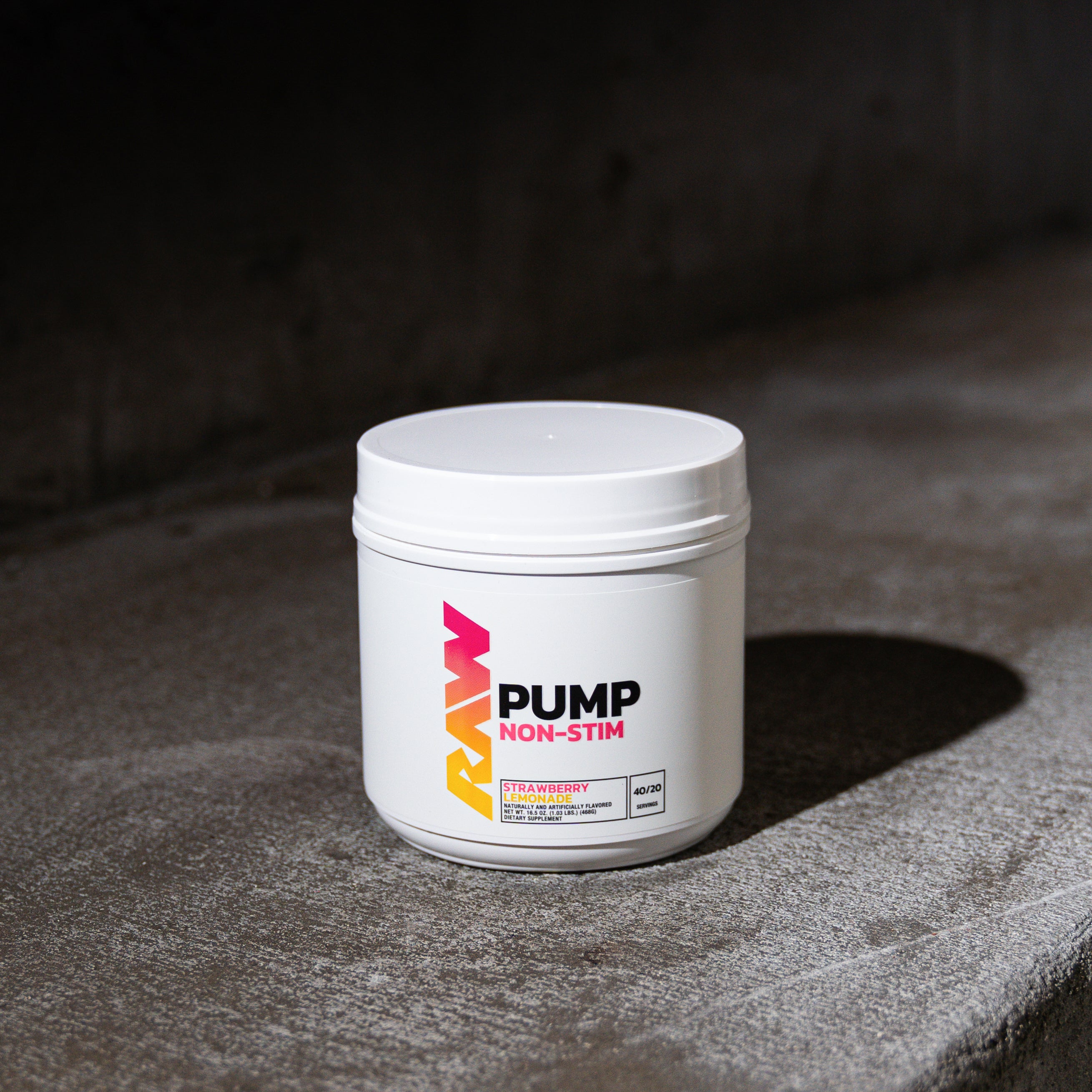 Container of workout supplement on a textured concrete surface.