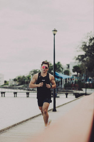 A man out for a run outside, wearing a black t-shirt and shorts