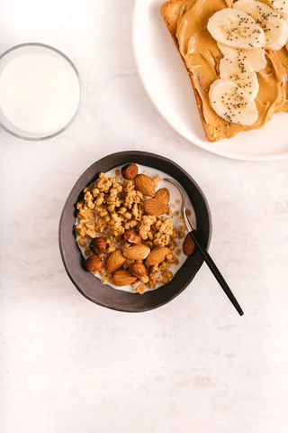 A bowl of Greek yogurts with nuts, and a piece of bread with peanut butter and bananas