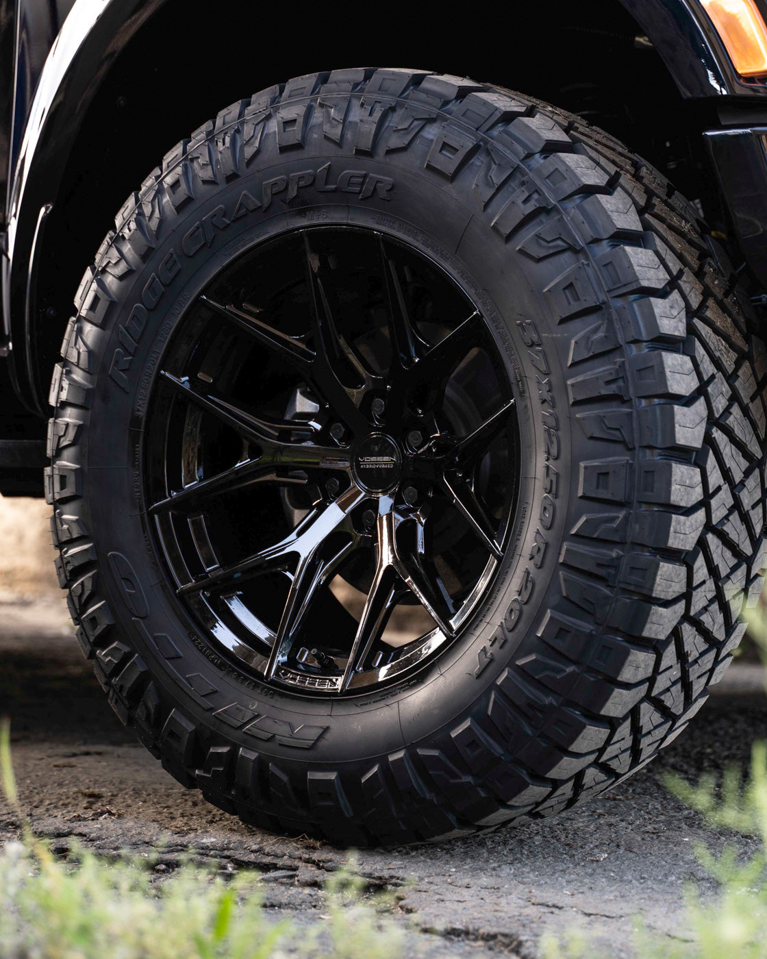 Close-up of a black off-road vehicle wheel with rugged tire tread.