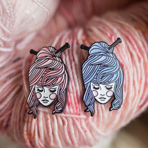 enamel pins of a girl with knitting needles in her hair, in pink and blue