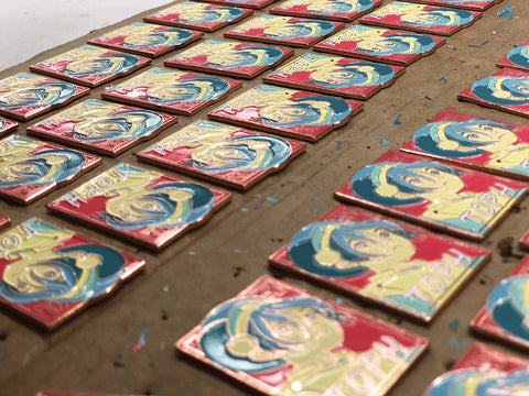 a tray of enamel pins curing after being inked