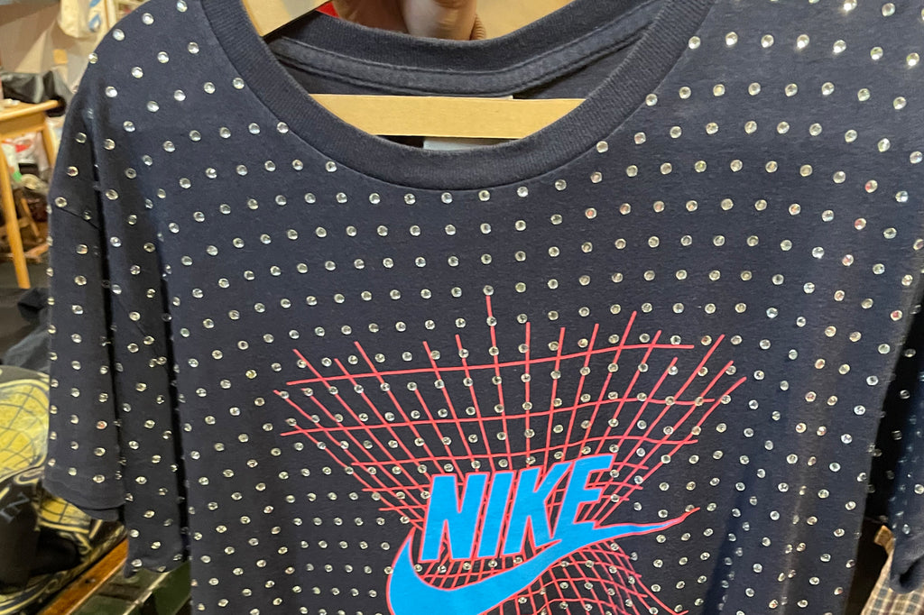 A bejewelled vintage blue logo Nike t-shirt with a centred red criss cross pattern.