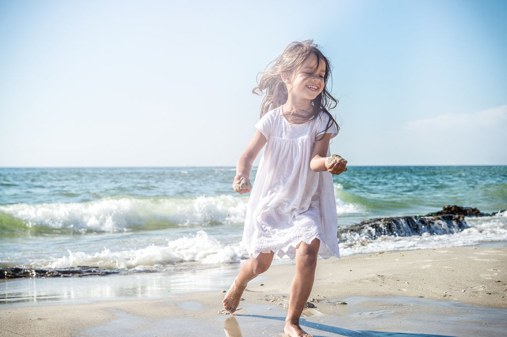Girl in pretty sundress running along the beach