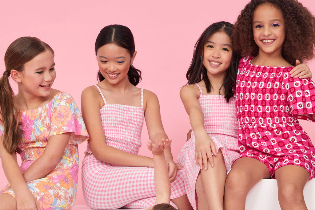 A group of tweens wearing Spring fashion by Gen Woo including gingham prints, fun playsuits and Spring flowers.