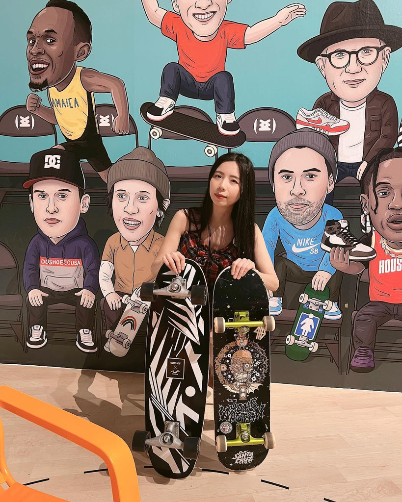 Young female skater shows colourful skateboard decks, in front of a caricature background