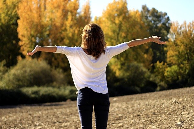 A woman facing nature with her arms open wide, breathing