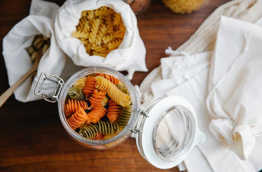 Colourful rotini and fusilli on table with cloth produce bags