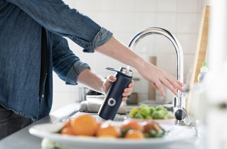 Filling up a water bottle with tap water.