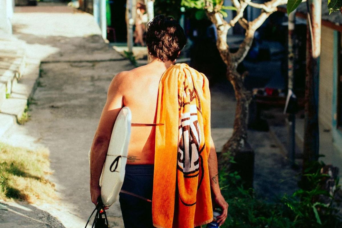 girl with surfboard and organic beach towel