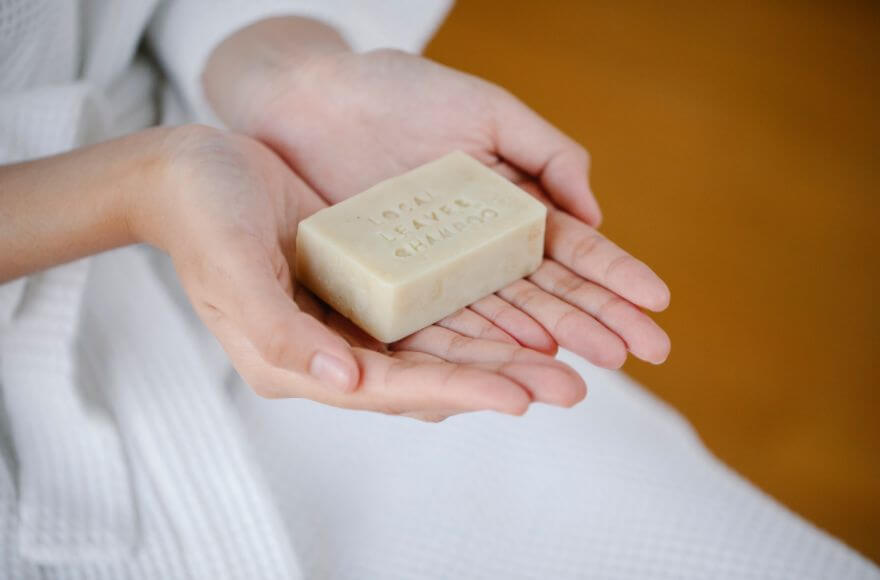 Woman holding eco shampoo bar in both hands.