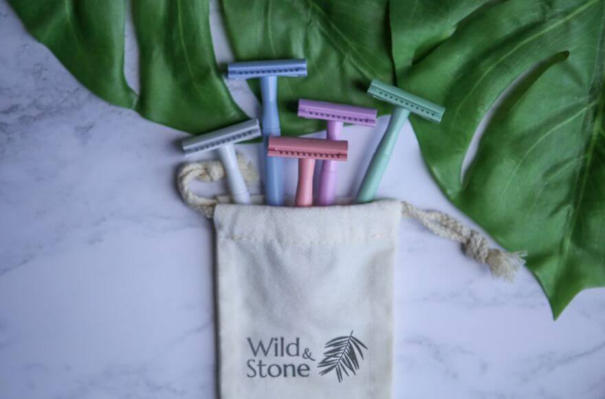 Five different coloured eco razors laid on a marble background.