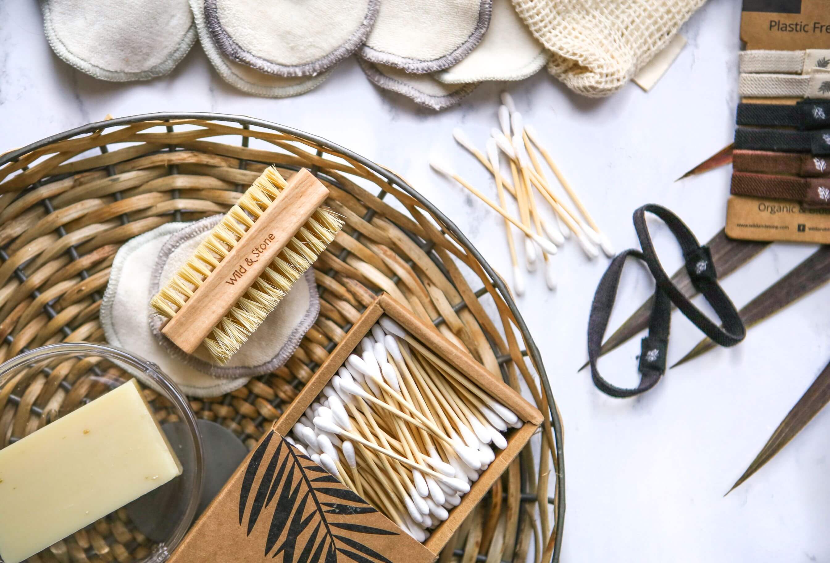 Open package of bamboo cotton buds sitting on a wicker table.