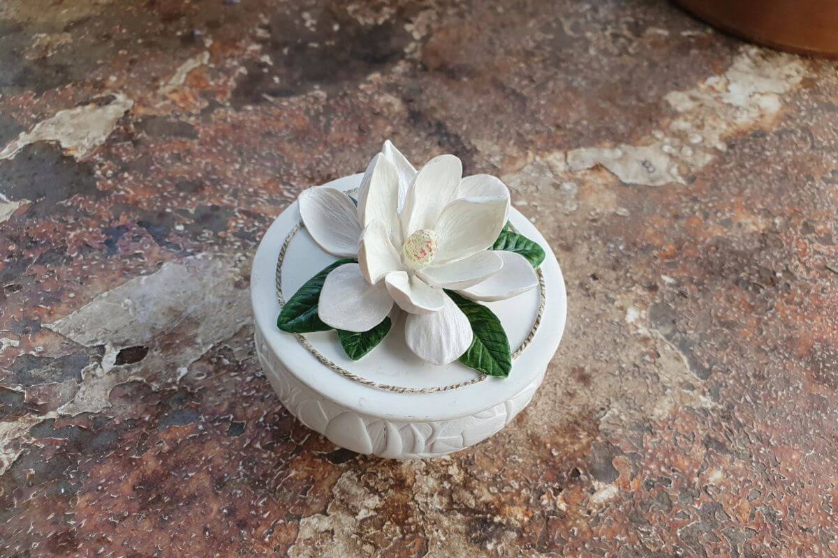 Trinket dish candle with a white flower on top.
