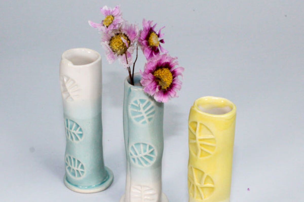 Handmade trio of mini stem vases with leaf prints on a blank background.