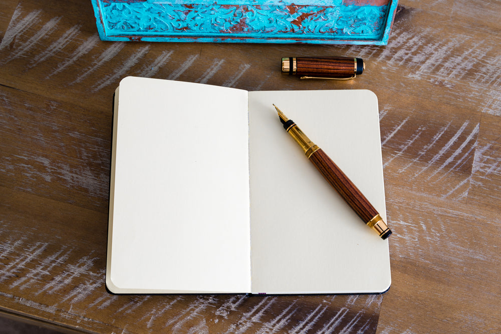 Classic fountain pen and open notebook on wooden table