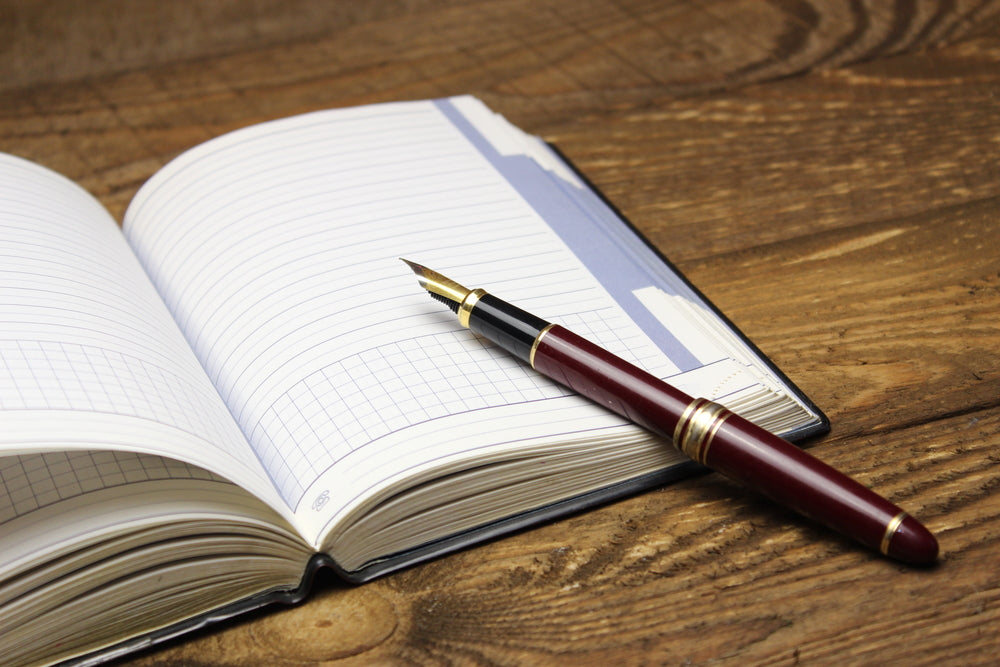 Notebook and fountain pen on a black wooden background