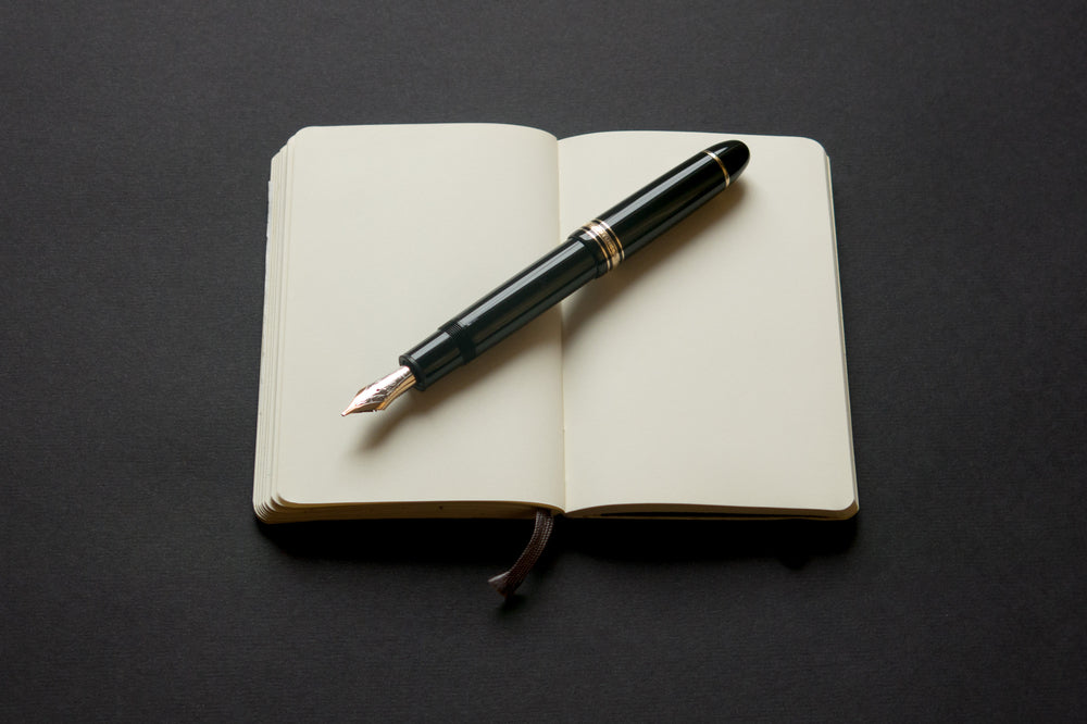 Open moleskin notebook and fountain pen
