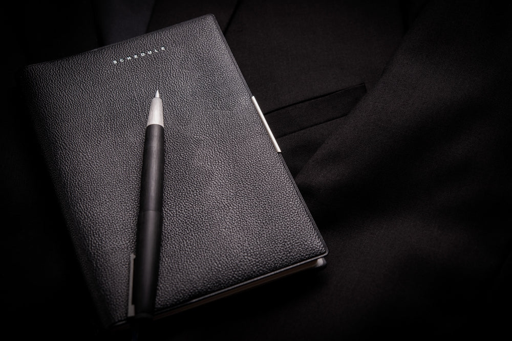 Personal organizer with fountain pen on black background