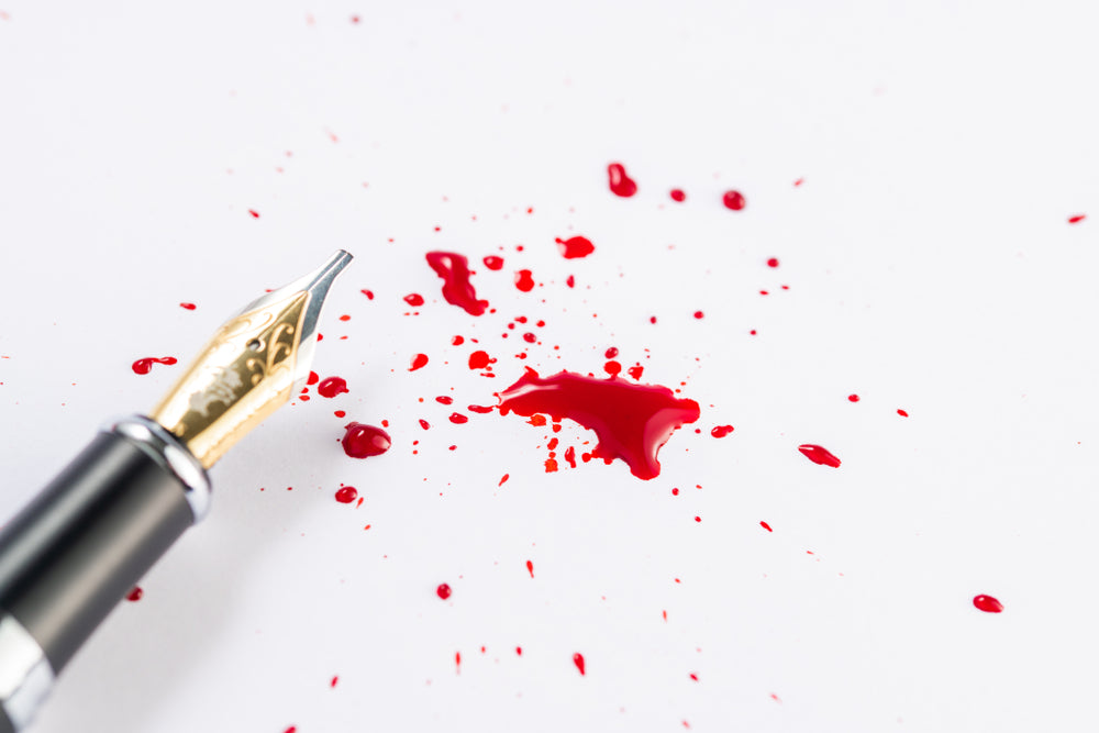 Splatter of red fountain pen ink on an isolated white background