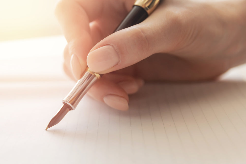 Young woman writer writes poetry with fountain pen on sheet of paper, warm sunlight.