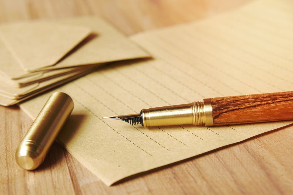 envelope , empty paper and fountain pen on table .