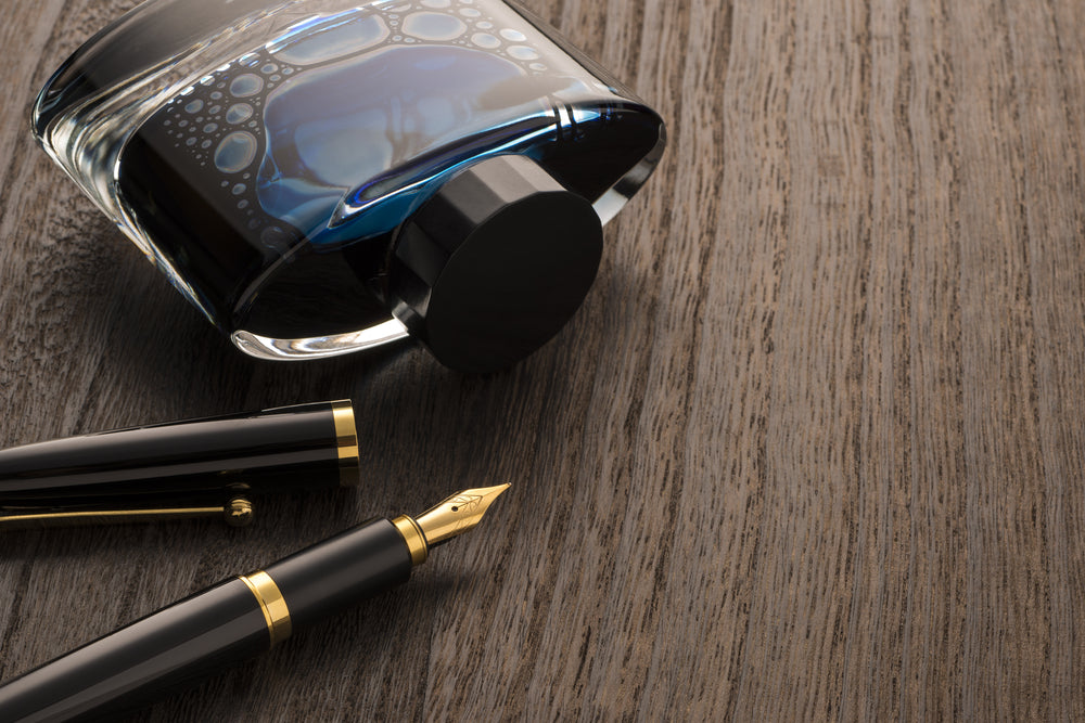 fountain pen and ink bottle on table 