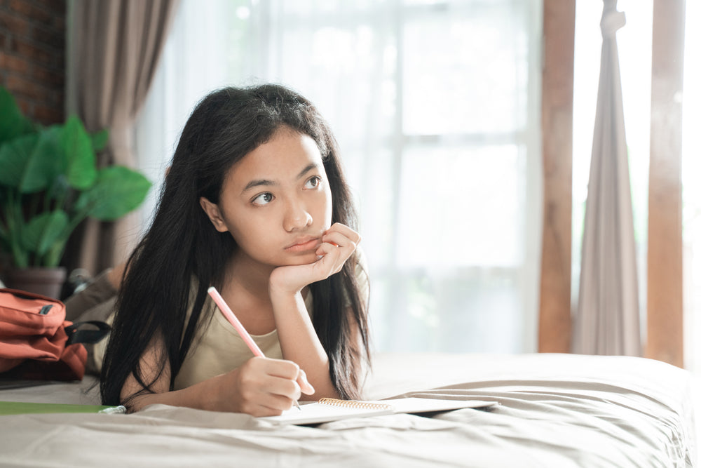 girl writing in a journal and thinking