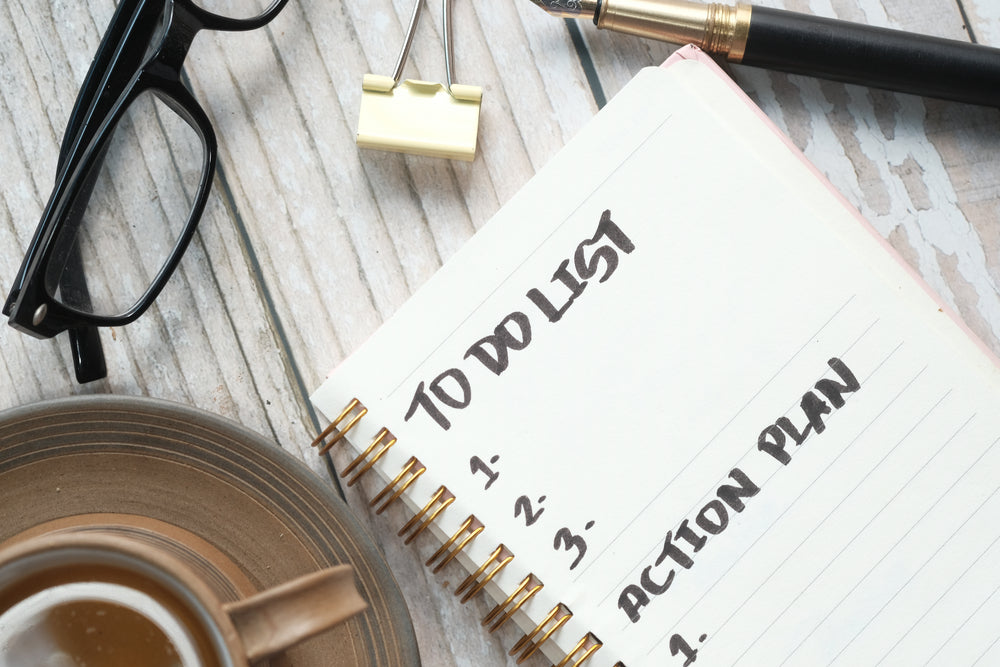 tea cup and journal with to do list on wooden table.