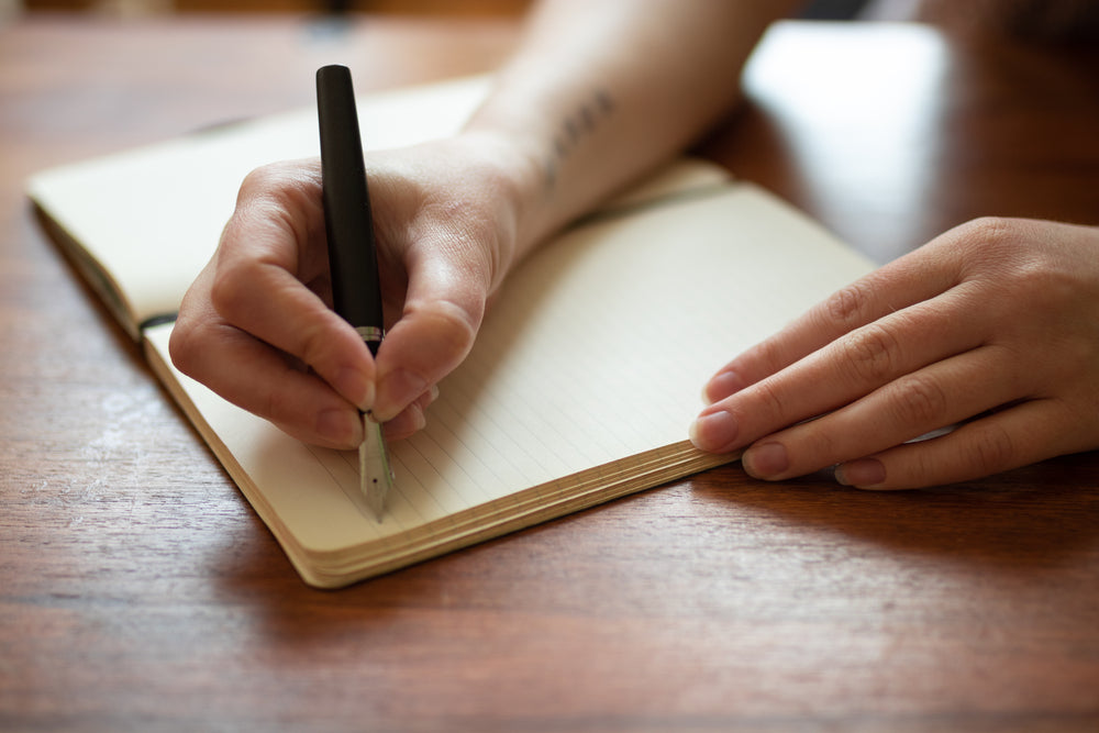 writing in a journal with a pen