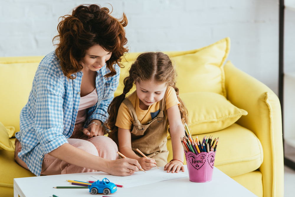 young babysitter and adorable kid drawing with pencils together