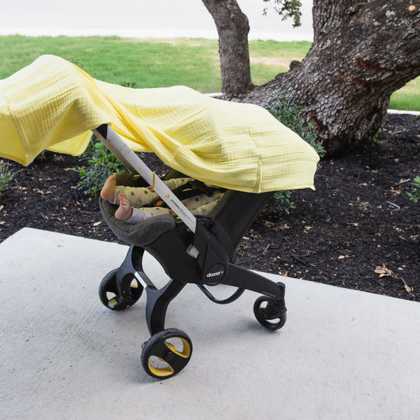 yellow muslin swaddle draped over baby stroller