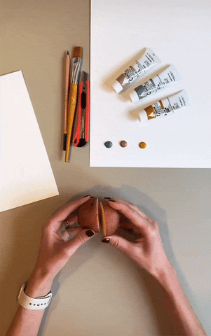 GIF of two hands tracing a shape on half of a cut potato with a pencil