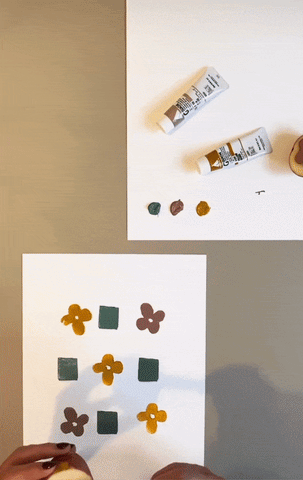 GIF of someone using a square shaped stamp made out of a potato, filling a page with a teal square pattern