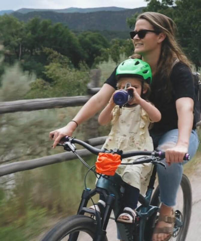 Woman and child riding bike while drinking from cup holder