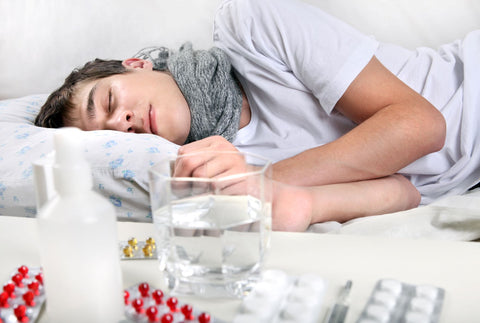 Tips to Ensure a Good Night's Sleep when sick, man sleeping deeply with pills and medication on night stand