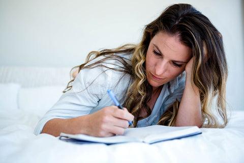 Journal dreaming in the waking state, woman writing journal in bed