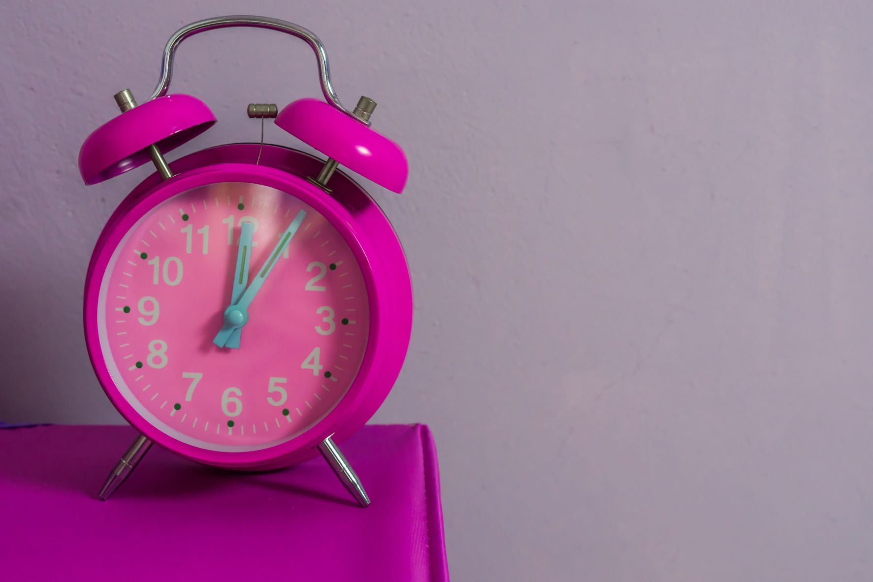 Is it okay to sleep 12 hours a day?, vintage pink alarm clock on bedside table