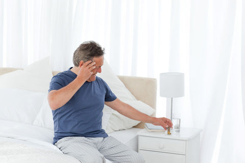 How can sleep apnea cause headaches, man waking up with headache and reaching for pills