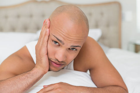 How To Fall Asleep With a Toothache, man holding his teeth with pain in bed