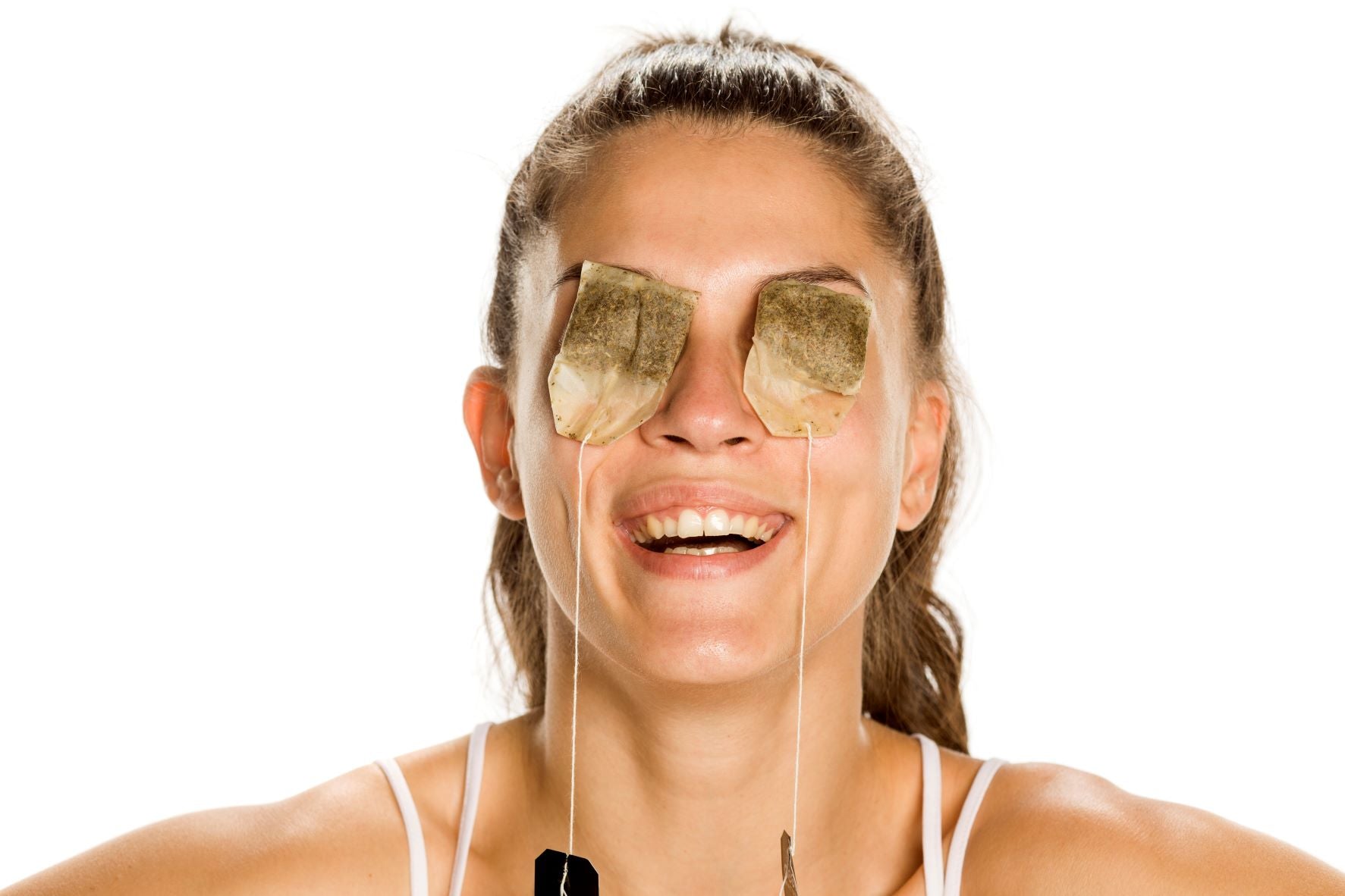 Woman having tea bags on her eyes laughing