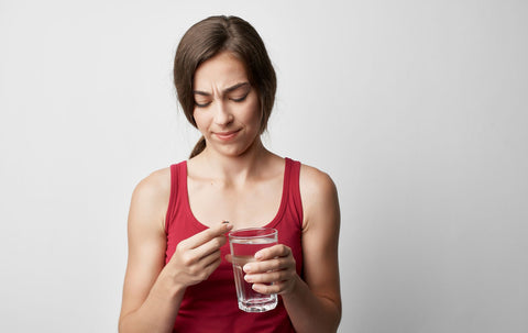 Woman looking at pill before taking it