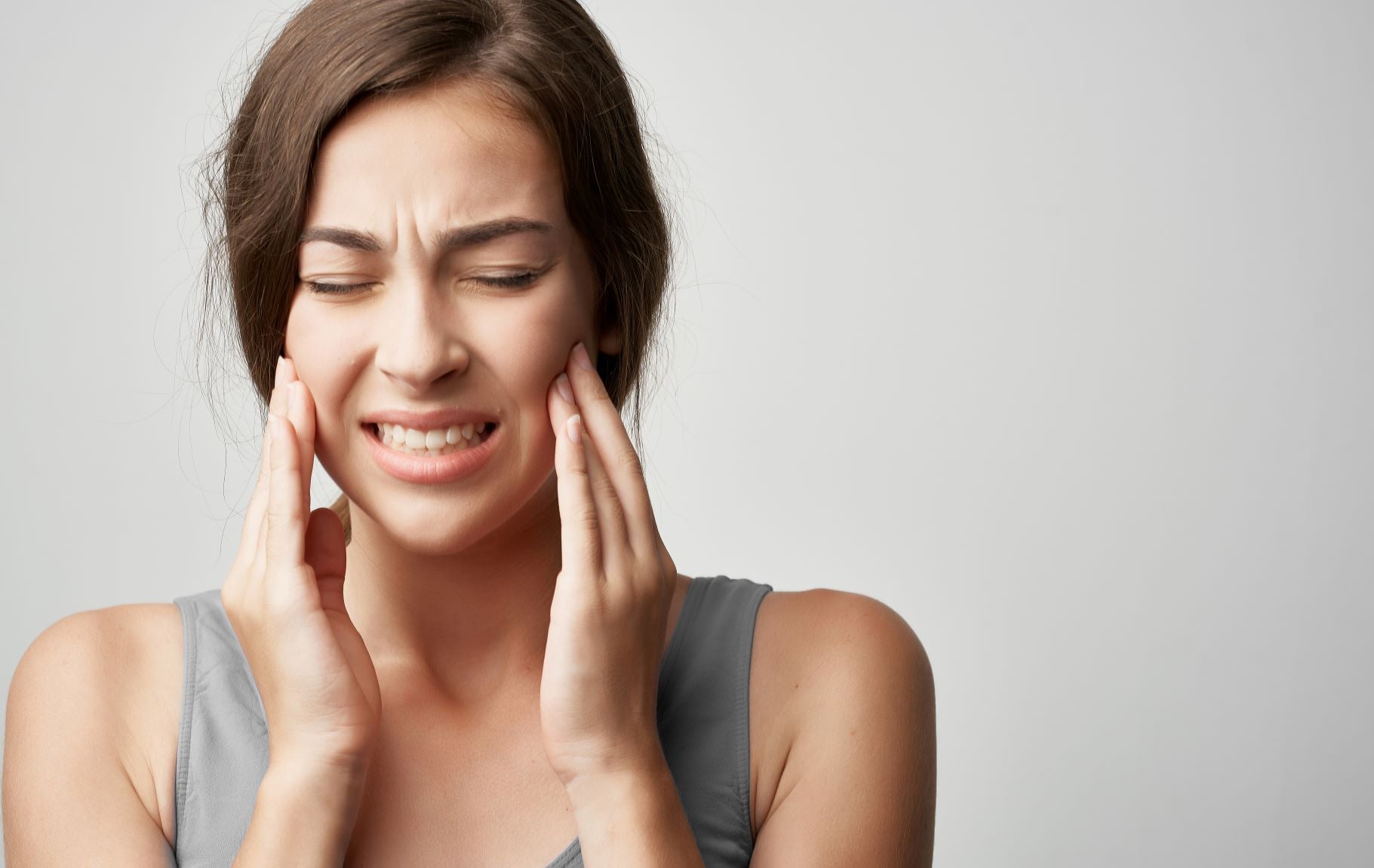 Jaw pain, teeth grinding, clenching are signs that you might need a mouth guard; woman holding jaw in pain
