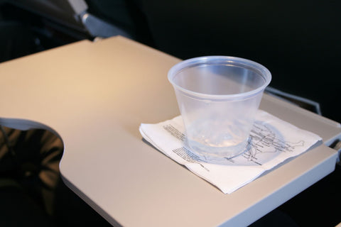 water cup on air plane tray table, stay hydrated during flight 